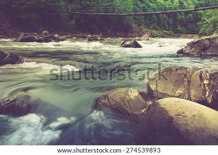 Landscape with mountain river flowing over rocks at summer. Filtered image:cross processed vintage effect.