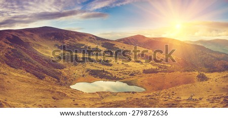 Panoramic view of mountain lake with sunlight.  Filtered image:cross processed vintage effect.