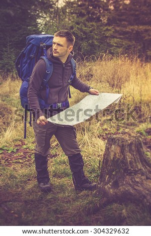 Backpacker with map to find directions in wilderness area. Filtered image:cross processed vintage effect.