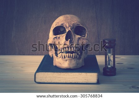 skull and book with vintage color tone on wood