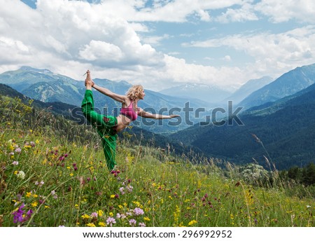Young slim woman makes yoga poses on the mountains
