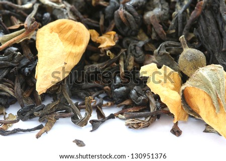 Dry black tea flavored with dry flower buds on white background