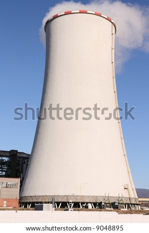 Huge chimney with smoke above it against blue sky in petrochemical factory