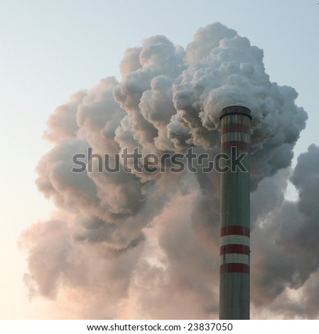 Thin chimney in coal power plant with huge dark smoke stack.
