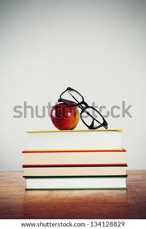 Glasses and apple on a pile of books.
