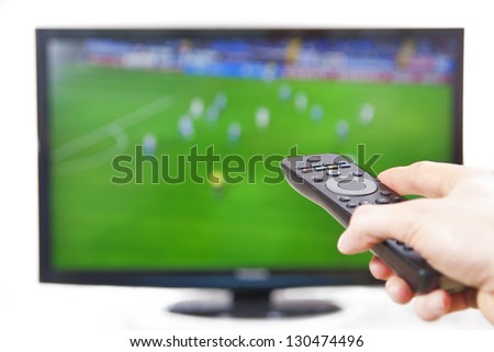 Hand pointing TV with remote controller sports in background