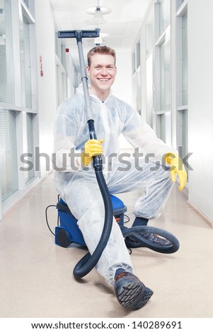 Office cleaning man taking a break sitting on hoover