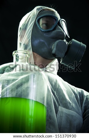 Man with gas mask and protective suit carrying hazardous chemical waste