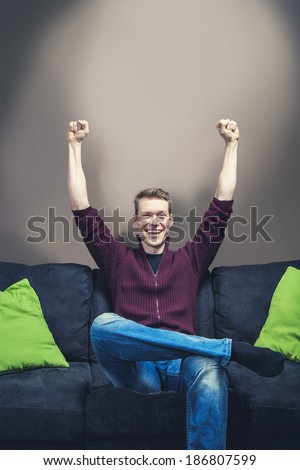 Man sitting on sofa celebrating hands on the air