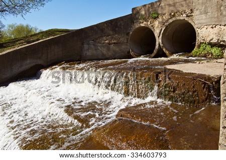 Water flowing out of two concrete drain  pipes.
