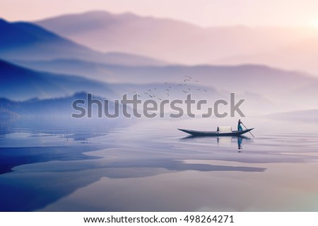 man riding boat in a  foggy winter morning infront of a beautiful  mountain in lake in bangladesh