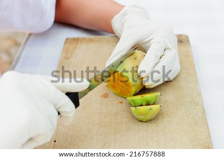 Hands covered with latex gloves peeling prickly pear fruits