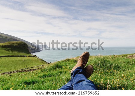 Man laying on the ground in a grass field, resting on a hill in the County Antrim, Northern Ireland