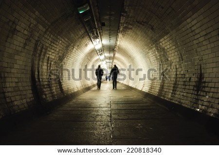 Two people walking in the dark tunnel