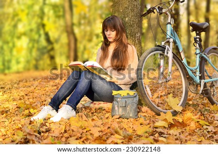 girl reading a book in a park and bike