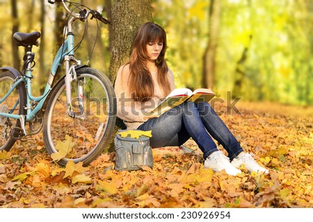 girl reading a book in a park and bike