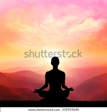Yoga silhouette on the mountain in the rays of the dawn sun