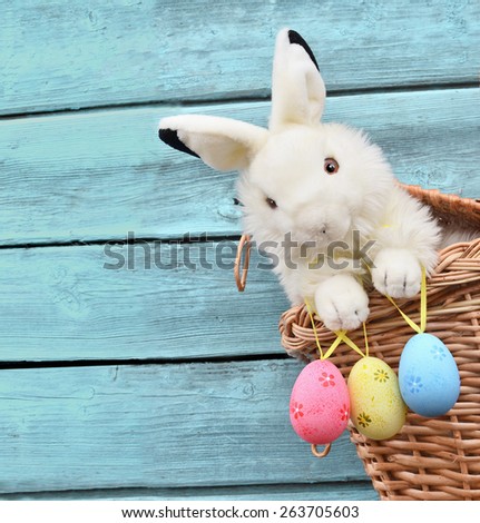 Happy Easter Bunny in a basket and eggs on a blue wooden background Happy Easter Bunny in a basket and eggs on a blue wooden background
