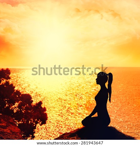 Silhouette of a woman sitting in profile on the beach. Yoga and meditation.