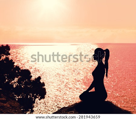 Silhouette of a woman sitting in profile on the beach. Yoga and meditation.