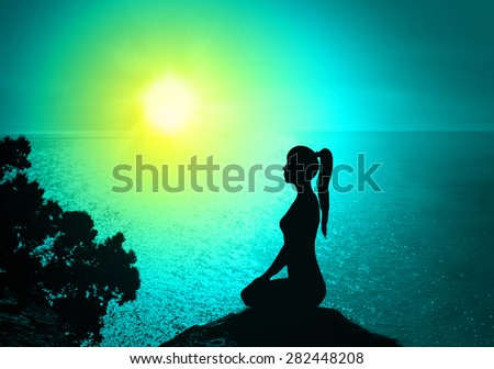 Silhouette of a woman on the beach at sunrise.Yoga and meditation.