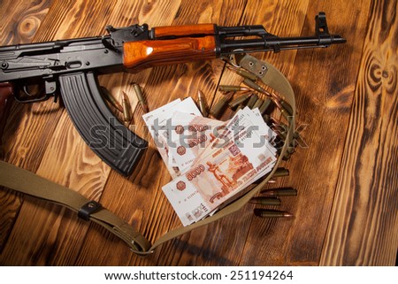 Kalashnikov rifle and Russian rubles on the table