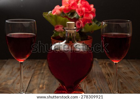 Bottle with red wine and flower on a wooden table