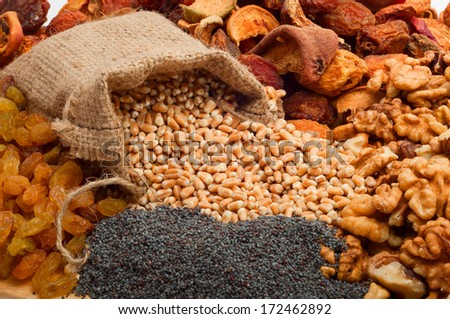 raw pearl barley in a canvas bag with dried fruit, raisins, nuts, poppy seeds on a wooden board