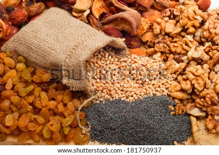 raw pearl barley in a canvas bag with dried fruit, raisins, nuts, poppy seeds on a wooden board