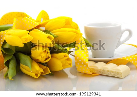 bouquet of yellow tulips with a cup of coffee and a slice of white chocolate on a white background