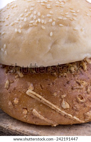 bun with sesame seeds and cheese on wooden background close-up