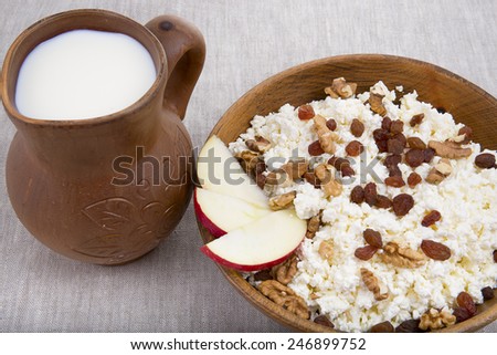milk and cottage cheese with raisins, nuts and apple in a clay pot natural