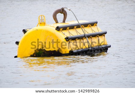 Large, bright yellow mooring buoy at sea with navigation light