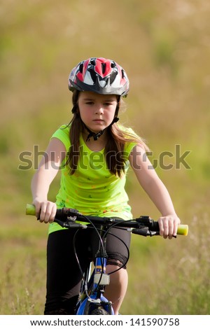 Portrait of teen girl in neon yellow shirt and a red helmet on a bike