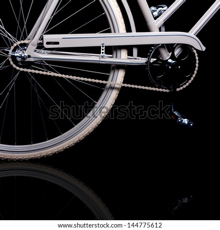 Old refurbished retro bike isolated on black background with reflection detail view of gears with chain and pedals