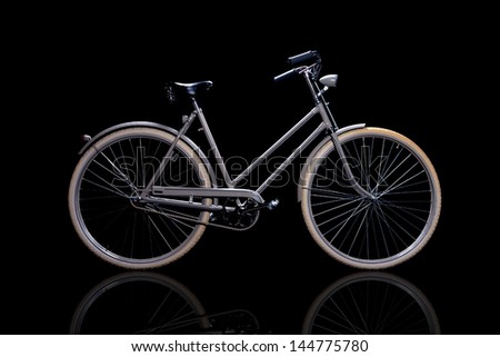 Old refurbished retro bike isolated on black background with reflection side view