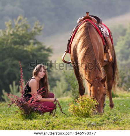 Young girl with long hair is squatting next horse breed Quarter Horse