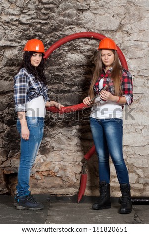 Two young long-haired woman looking cables for the repair of an old house
