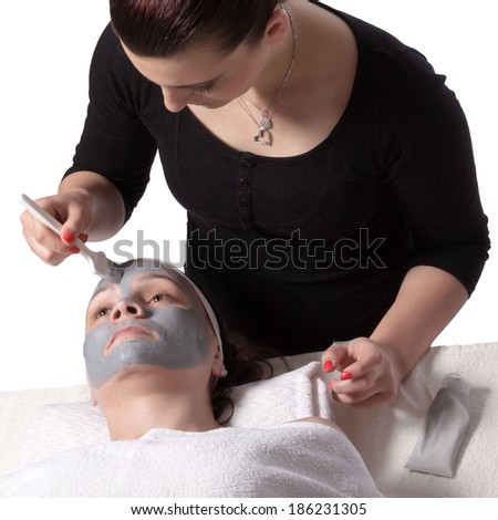 Beautician applied a young woman cosmetic facial mask with a brush