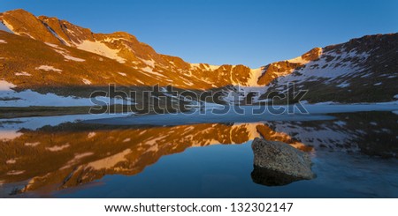 Summit Lake Panoramic. The glow from the early summer sun rising over the plains hits the peak of Mount Evans on Colorado\'s front range.