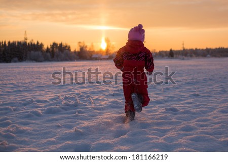 Child runs to meet the sun in winter