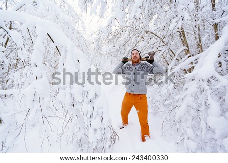 Lumberjack in the snowy winter forest. A man with a red beard and ax posing in a snowy winter forest.