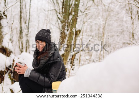Girl with a cup of tea in the winter forest