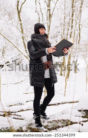 Girl with a book in the winter forest