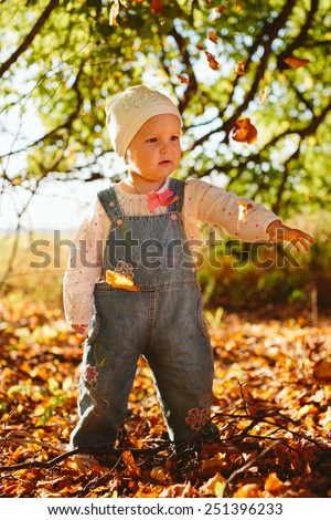 child throws autumn leaves