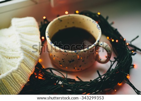 ?up of coffee in the center of the circle of the christmas lamp garland close up photo with cap.