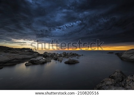 cloudy sunset over the sea in a rocky beach with stones and red dusk. epic sky