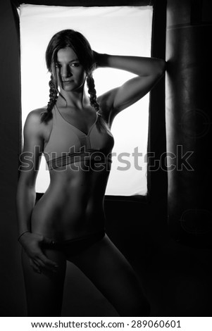 beautiful bikini fitness girl posing in a gym backlit. black and white