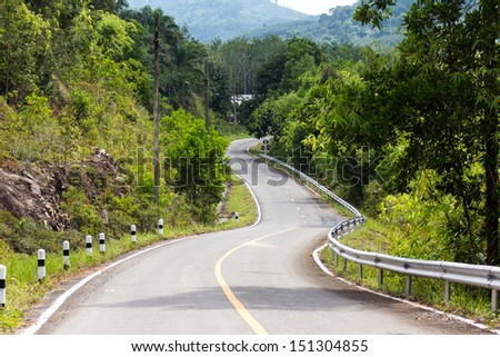 Road curves. Slopes down from the mountains.