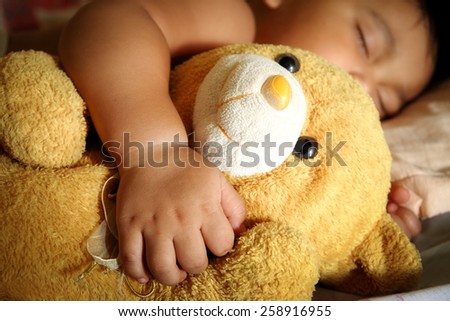 Blurry a child sleep with a teddy bear.